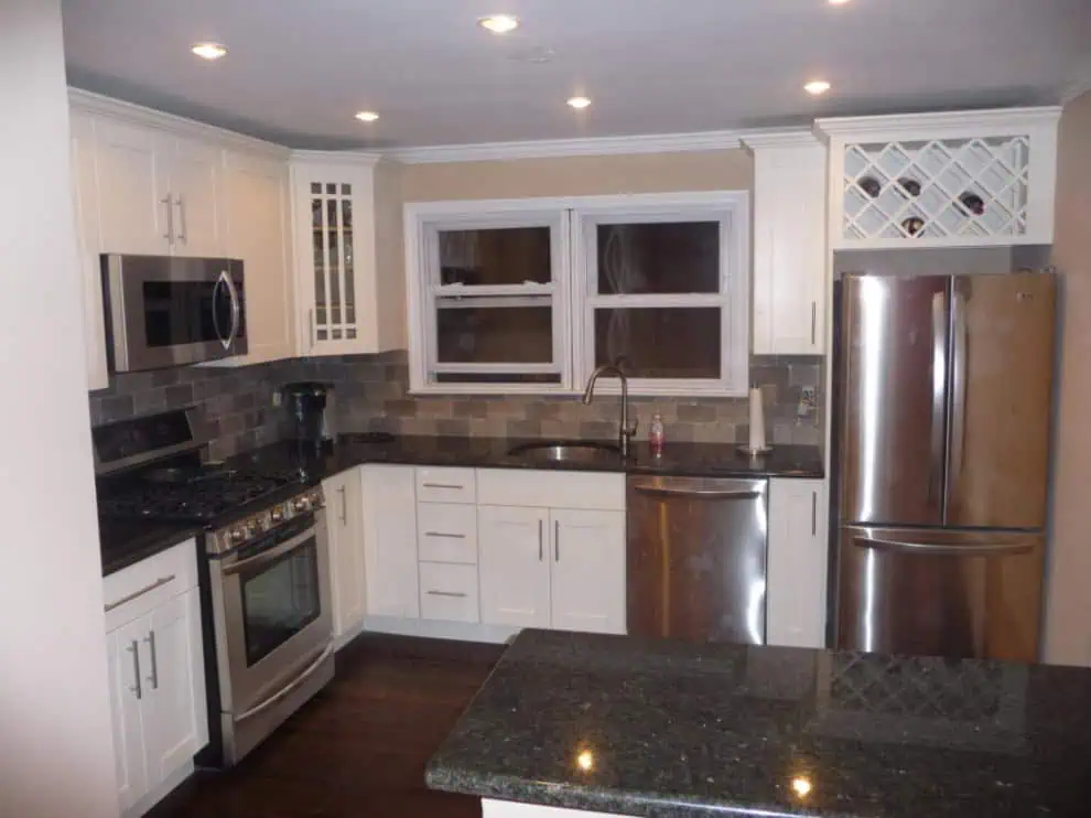 Home Remodeling: Modern kitchen with white cabinets, granite countertops, stainless steel appliances, and a wine rack.