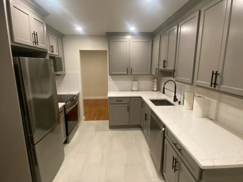 Modern kitchen interior with stainless steel appliances, gray cabinets, white countertops, recessed lighting, and home remodeling services.