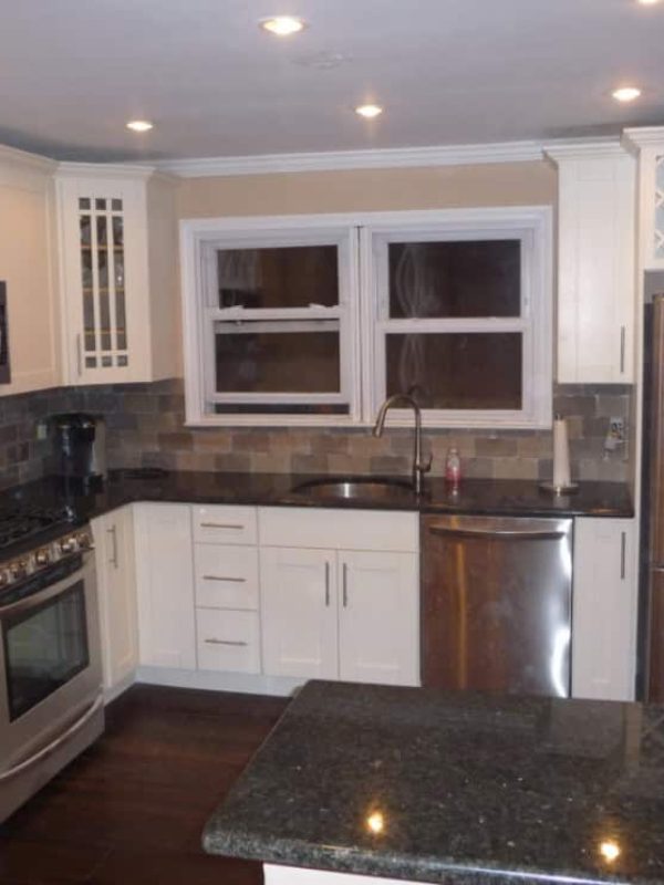 Home Remodeling: Modern kitchen with white cabinets, granite countertops, stainless steel appliances, and a wine rack.